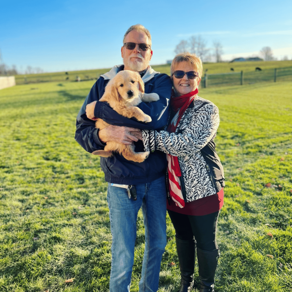 happy couple with golden retriever puppy